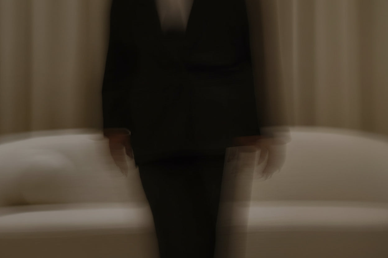 Close-up of a person wearing a dark suit in a softly lit room.